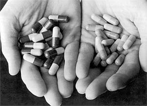 Two hands holding different color pills